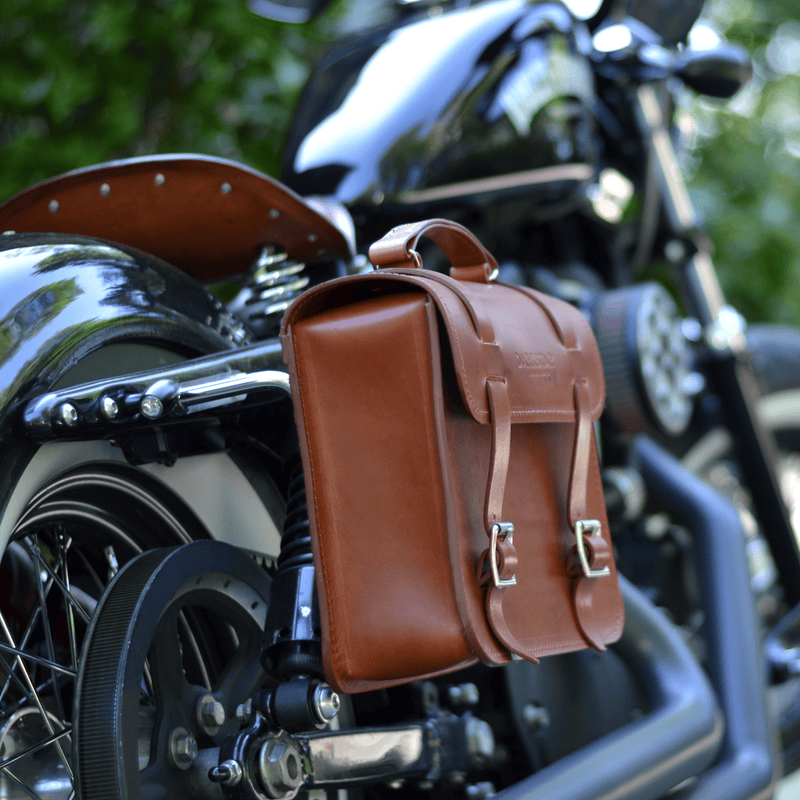 Nomad pannier in Tan leather attached to Harley Davidson Softail pannier rail - close up image of pannier with traditional brass roller buckles